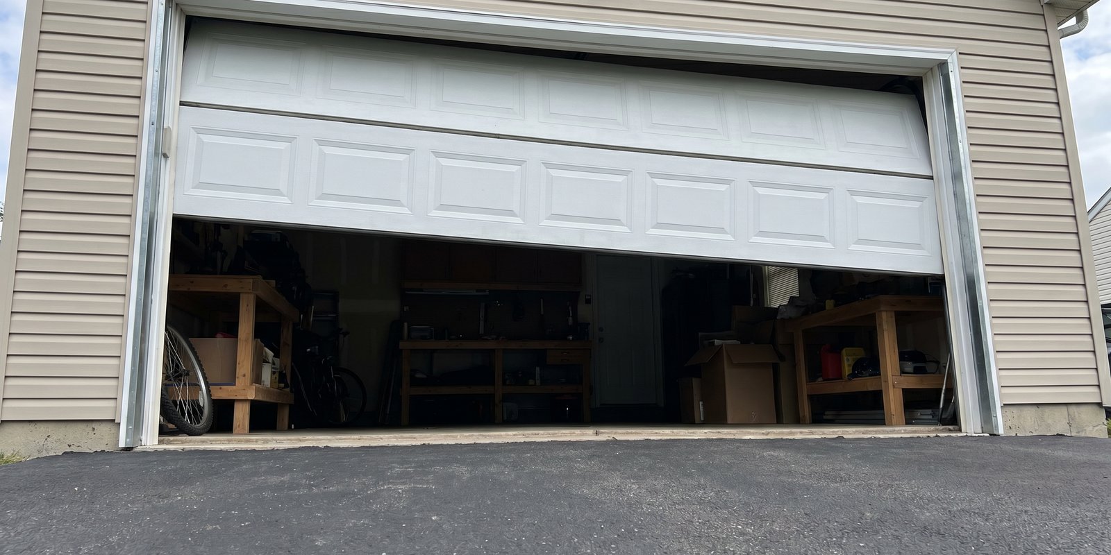 Garage door stuck partially open with one side dropped showing imbalance