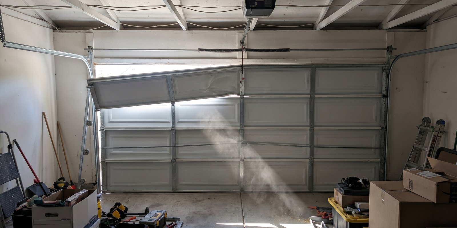 Garage door off track interior view with daylight streaming through gap at top